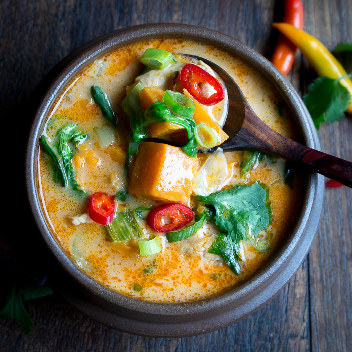 Creamy Thai Sweet Potato Chicken Soup showing chunks of sweet potato with the creamy broth in a wooden spoon. 