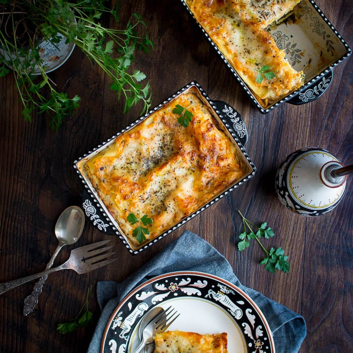 Freshly baked vegetarian spinach and mushroom lasagna in a pretty black and white baking dish.