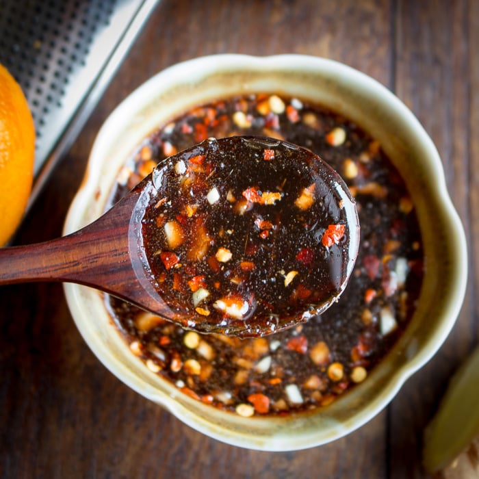Pomegranate and orange sauce getting mixed in a white bowl. 