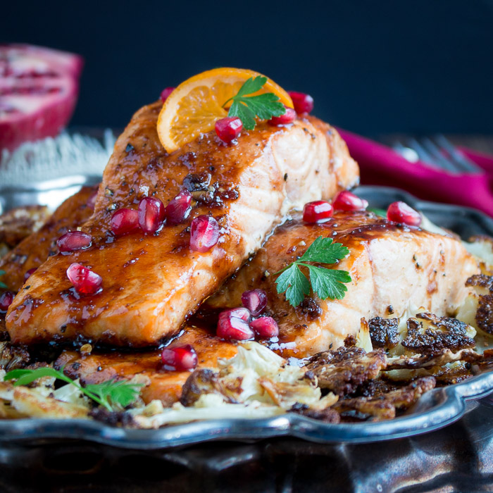 Baked Pomegranate Glazed Salmon on top of roasted cauliflower on a silver platter.