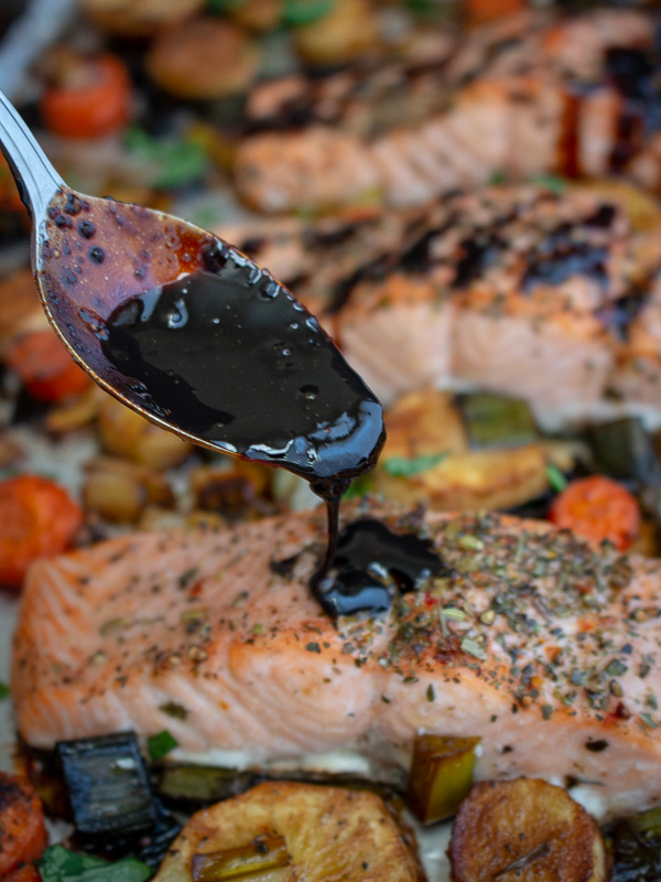 Balsamic glazed getting drizzled over baked salmon fillets.