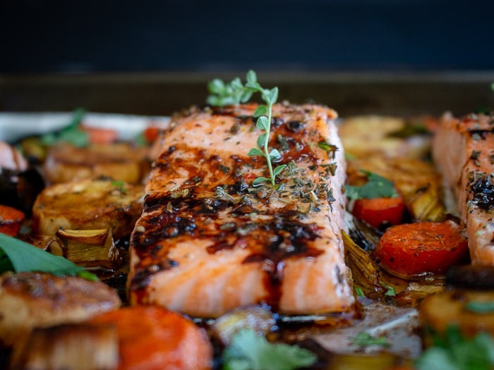 Balsamic Glazed Salmon and Roasted Root Vegetables garnished with fresh thyme leaves. 