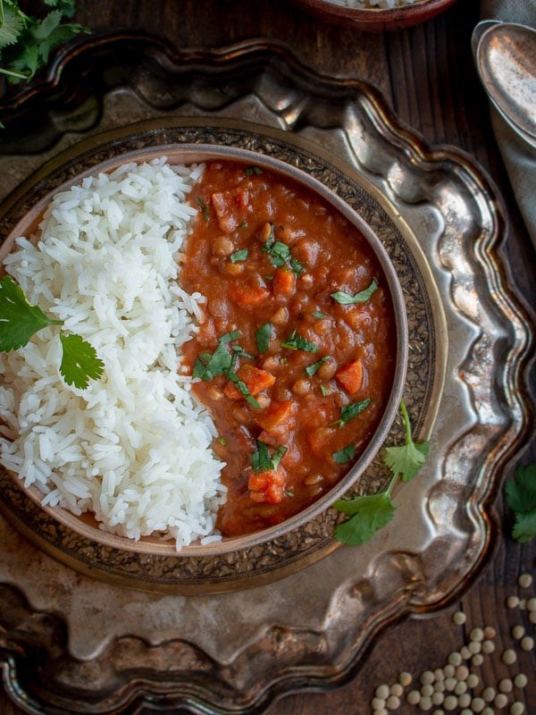 Top down photo showing the ham and lentil stew on plate with a silver plate underneath.