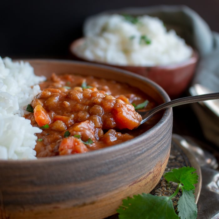 Spoonful of Instant Pot Lentil Ham Stew with rice in a pottery bowl.