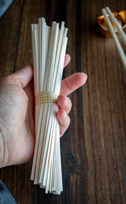 holding dry lo mein noodles in hand. 