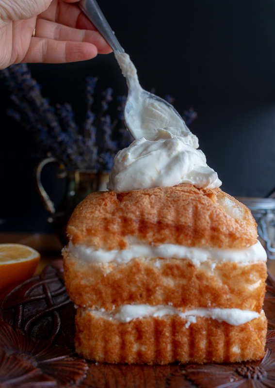 Placing a large dollop of coconut whipped topping on top of angel food icebox cake.