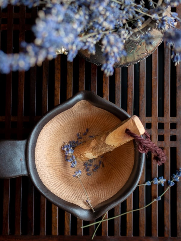 Lavender being crushed in a mortar and pestle.