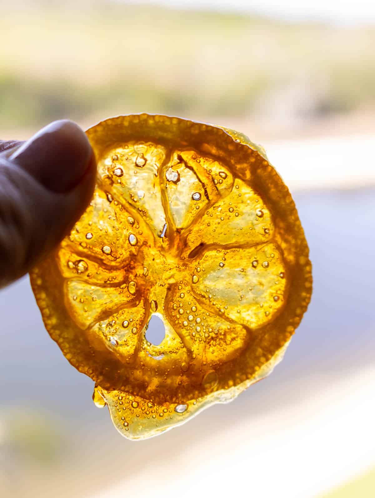 Stain glass window looking honey lemon candy held up to the sky.