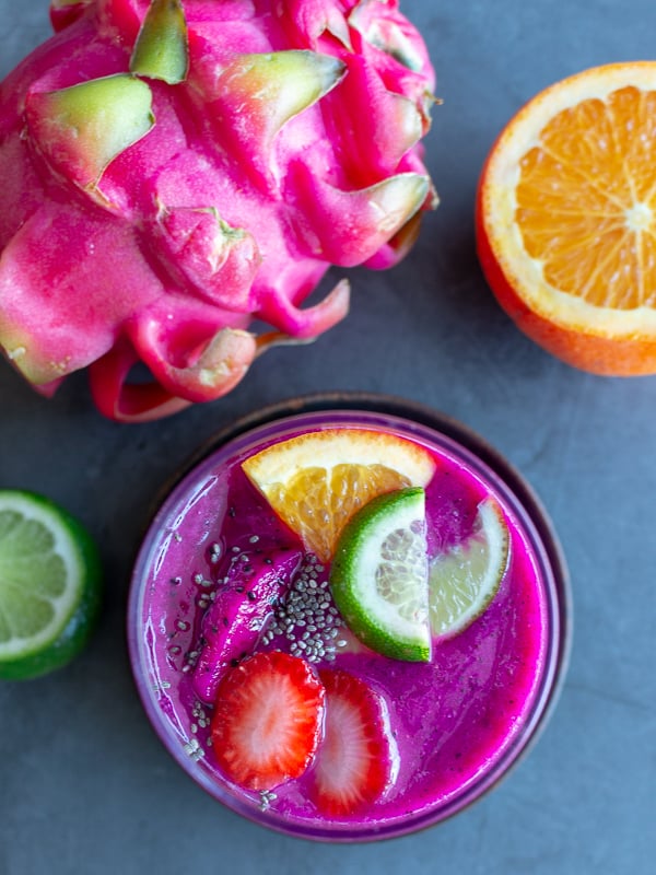 Top down shot of smoothie showing the toppings of fresh tropical fruit and a little chia seeds.