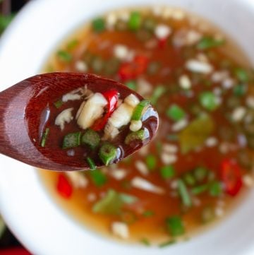 Spoonful of Prik Nam Pla sauce showing all the fresh herbs.