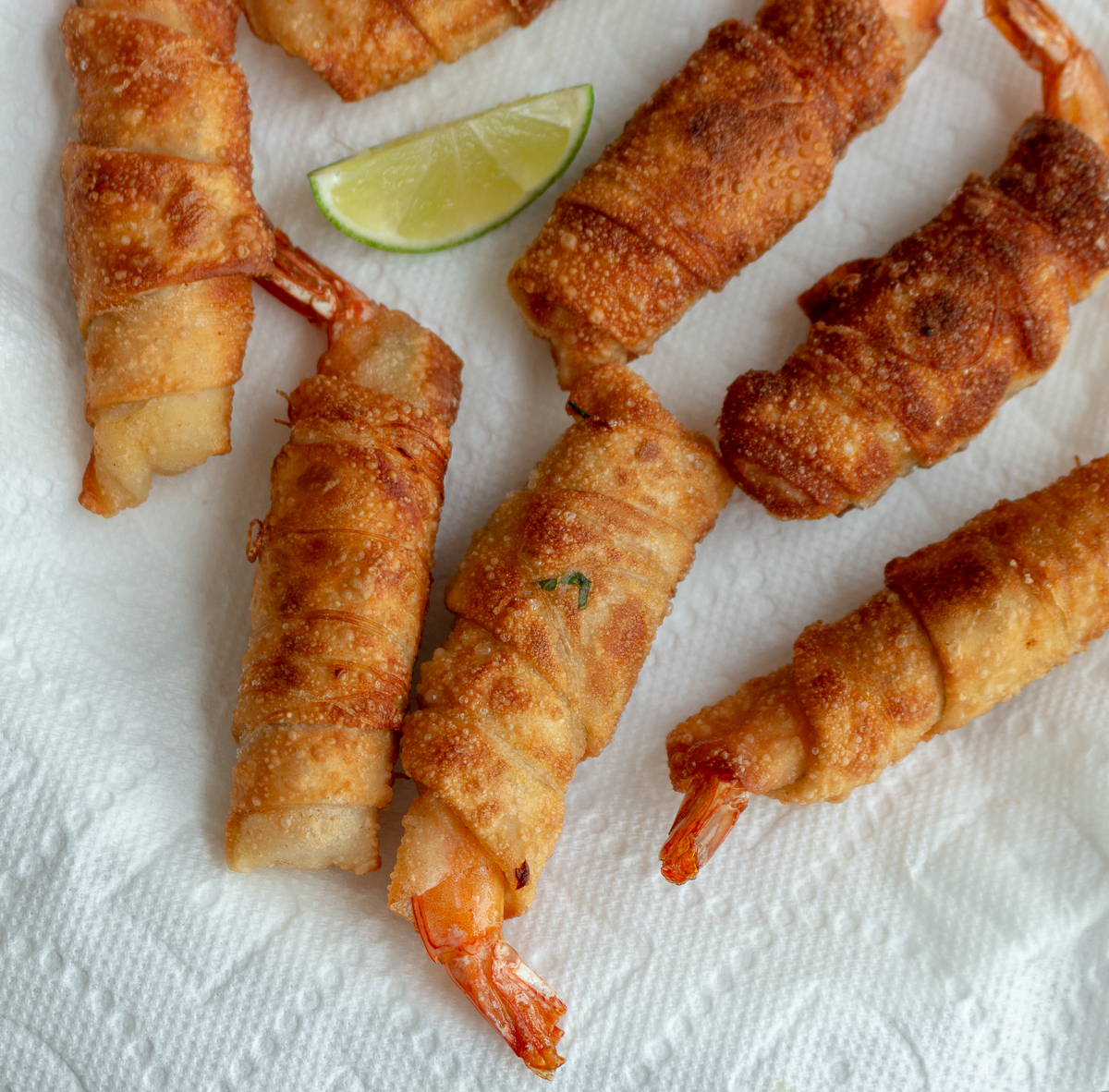 5 Thai Firecracker Shrimp appetizers laying a a lined white plate with limes.