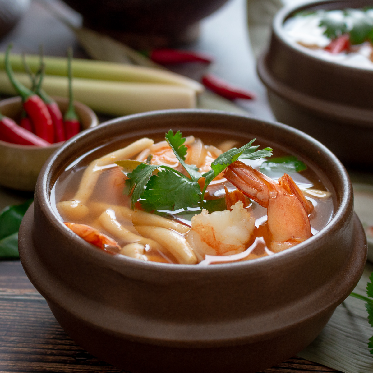 Delicious bowl of Thai Hot and Sour Prawn Shrimp in a brown rustic bowl garnished with fresh cilantro.