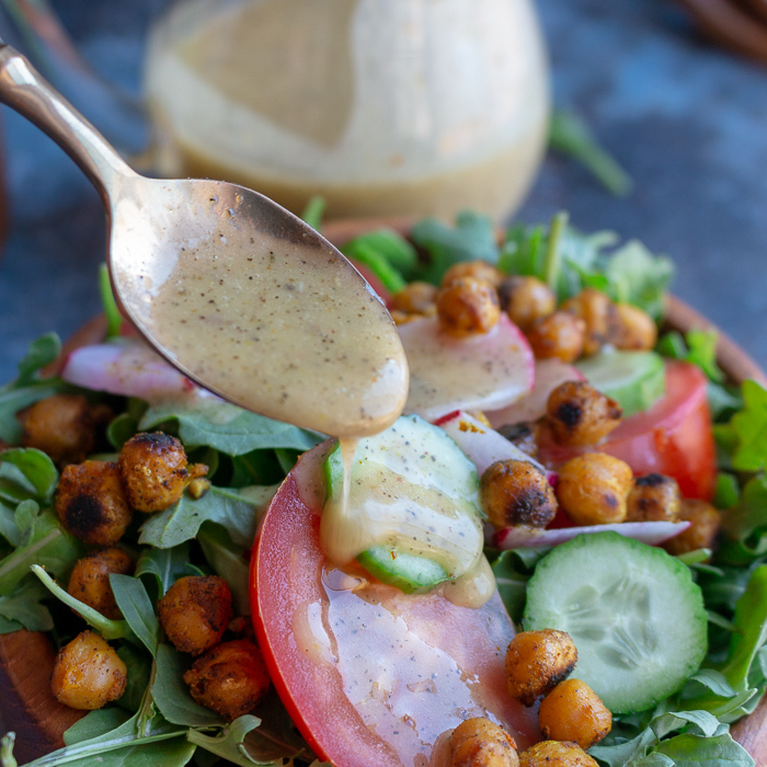  Little extra vinaigrette drizzled with a spoon over a salad.