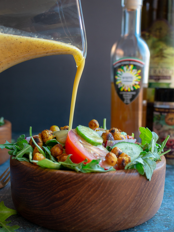 Vinaigrette getting poured over a salad.