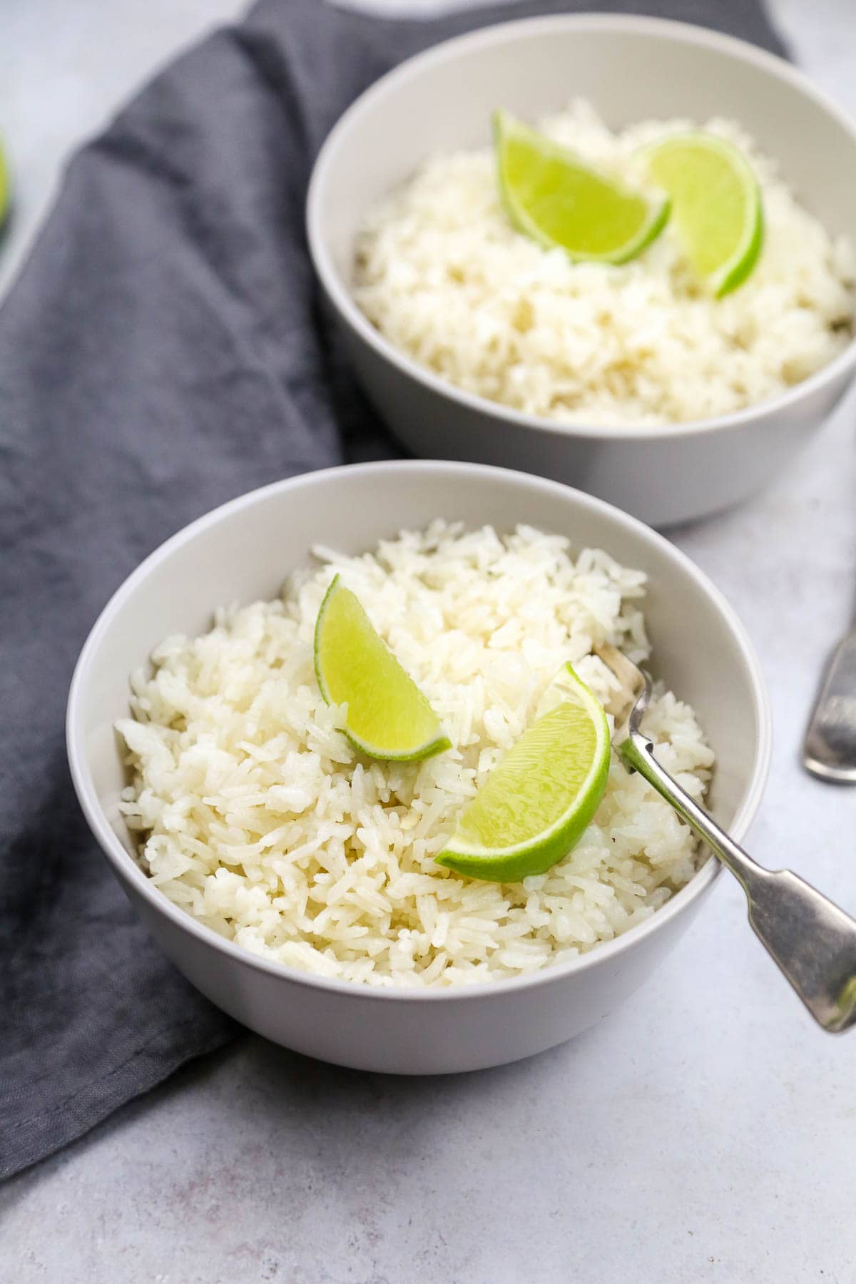 Coconut rice served in 2 bowls garnished with fresh limes