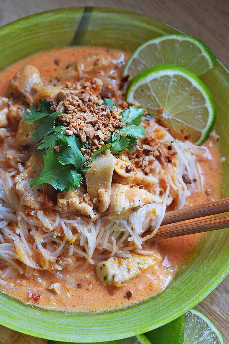 Red coconut curried chicken with lemongrass and sesame noodles. Garnished with peanuts, cilantro and lime. 