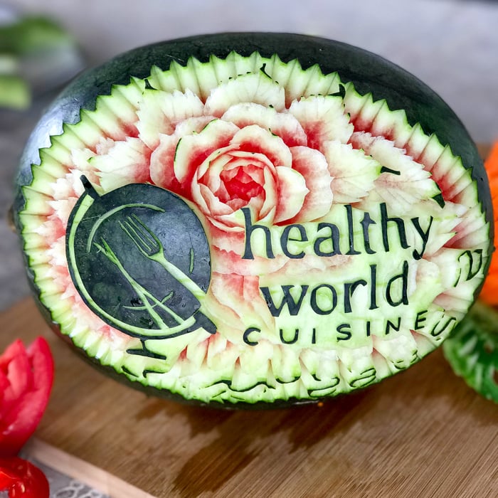 Carving of a watermelon with healthy world cuisine and our logo.
