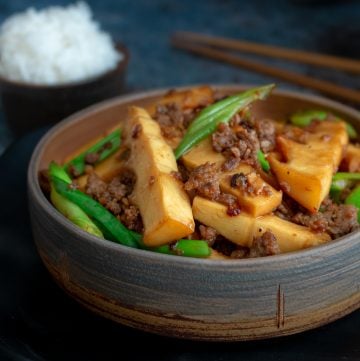 Spicy Pork and Bamboo Stir Fry in a handmade beige and gray pottery bowl with white rice and chopsticks.