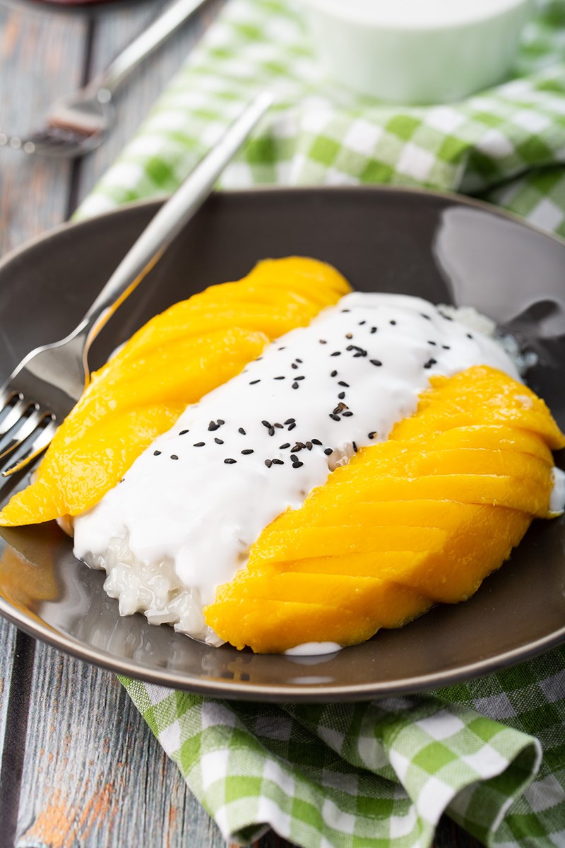 mango sticky rice with coconut cream on top of rice