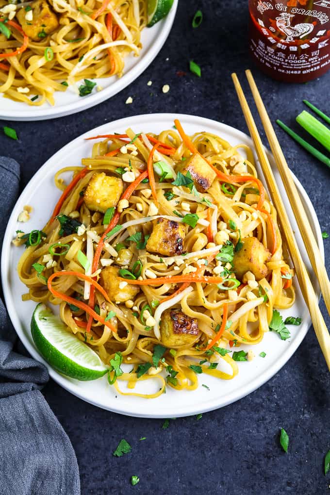 Vegan Pad Thai with tofu and noodles garnished with limes