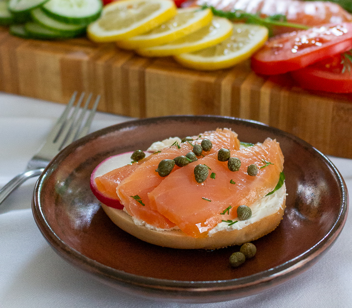 Bagel with cream cheese, lox, radish, cucumber, capers and a little dill on top.