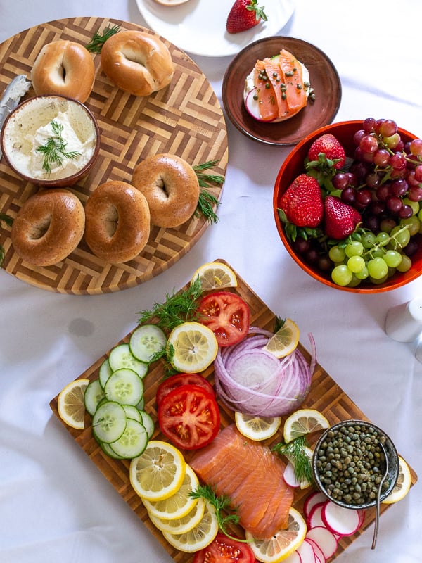 Top down shot of bagel bar with assembled bagels and a bowl of seasonal berries and grapes.