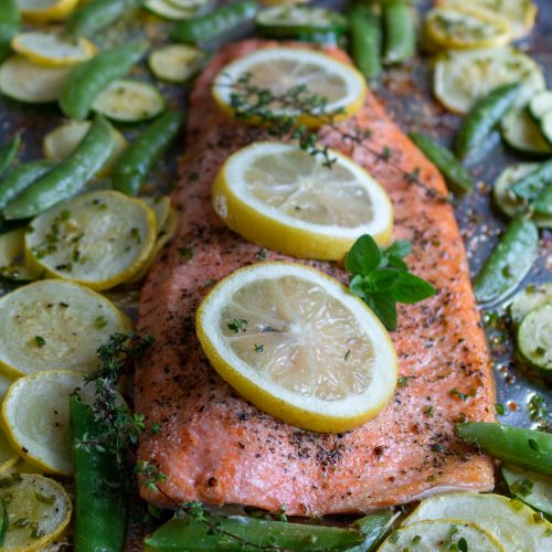 Lemon Herb Baked Rainbow Trout on a sheetpan hot out of the oven with fresh lemon slices and herbs on top.