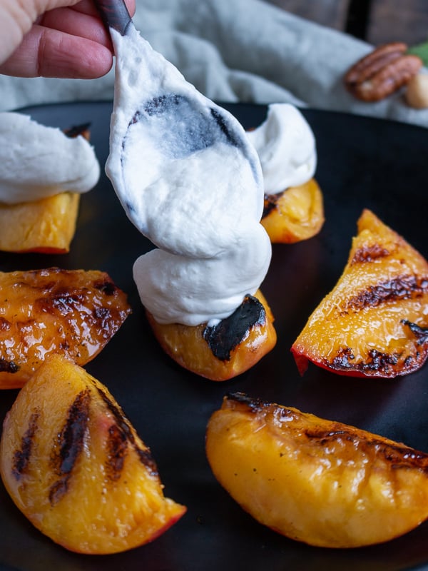 Grilled nectarines getting a dollop of whipped coconut cream on top. 