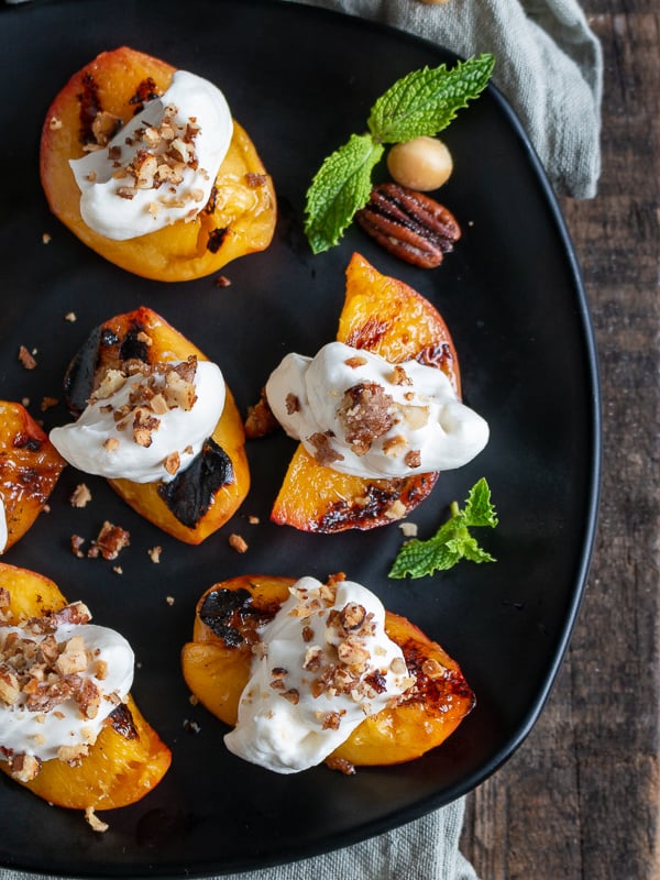 Grilled Nectarines with a dollop of whipped coconut cream and crushed candied nuts on each.