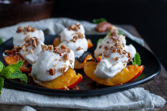 Grilled Nectarines with a dollop of whipped coconut cream and crushed candied nuts on each.