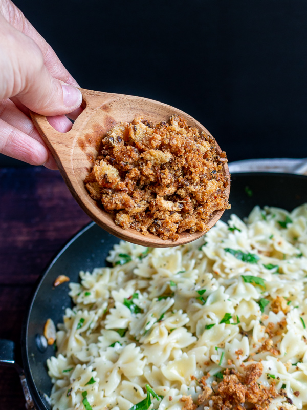 Toasty homemade bread crumbs getting added to freshly cooked pasta.