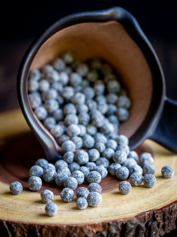 Uncooked boba balls or otherwise known as tapioca pearls pouring out on to the table in a brown bowl. 