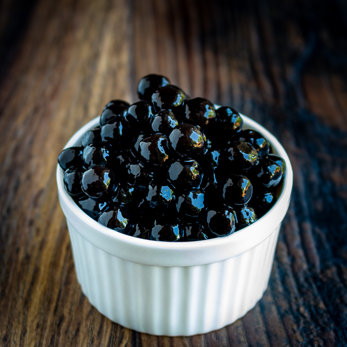 White bowl filled with cooked black boba balls - tapioca pearls.
