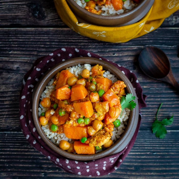 Bowl of Ground Turkey Sweet Potato Curry over a bed of rice in a brown bowl with a napkin hugging around it.