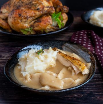 Bowl of Grandma's Chicken and sliders in a black bowl with mashed potatoes and roasted chicken with a whole roasted chicken in the background.