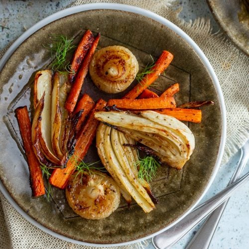 Balsamic roasted fennel, onions and carrots on a green plate with fennel as garnish.
