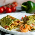 Shrimp Burritos with Creamy Poblano Sauce cut in half to show the shrimp and rice mixture on a white plate.