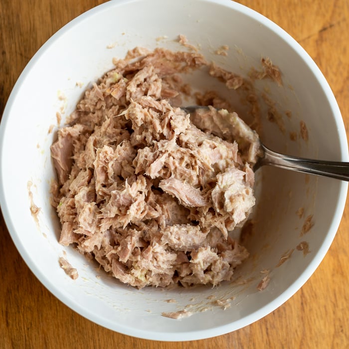 Tuna fish mixed with mayonnaise and wasabi in a white bowl.