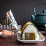Onigiri served 2 ways one with sprinkles and one in wrappers with a side of hot green tea.