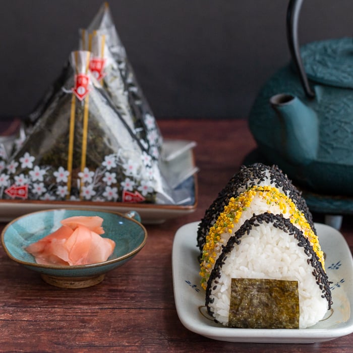 Onigiri served 2 ways one with sprinkles and one in wrappers with a side of hot green tea.