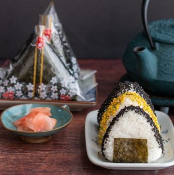 Tuna rice Mayo Balls with sesame sprinkles and some in onigiri packages with a tea pot.