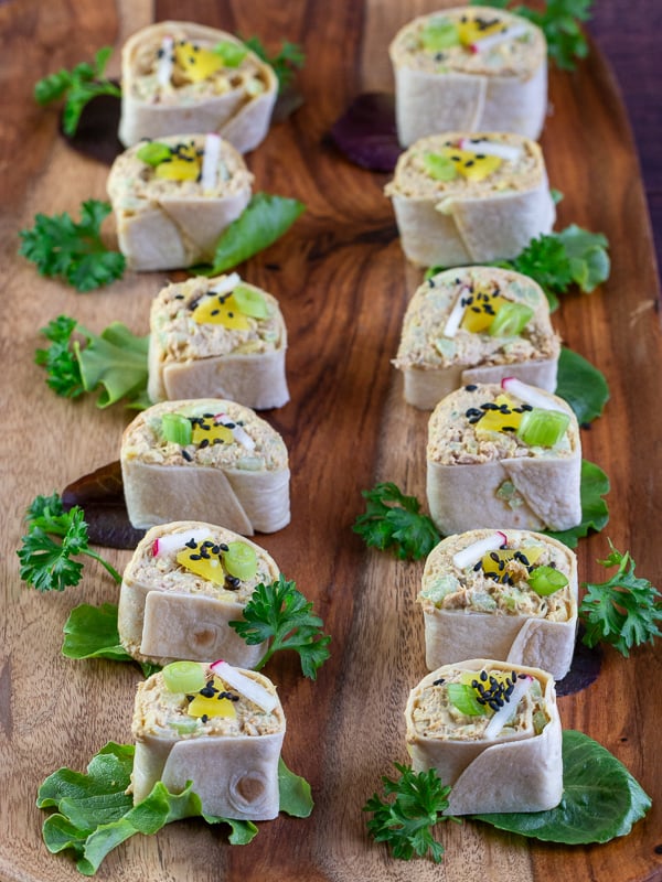 12 curry roll ups lined up on a wooden plate. 