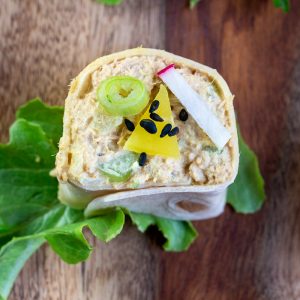 Close up top down shot of completed Curried Tuna Salad Roll Up garnished with blacks sesame seeds, diakon pickles and green onions.