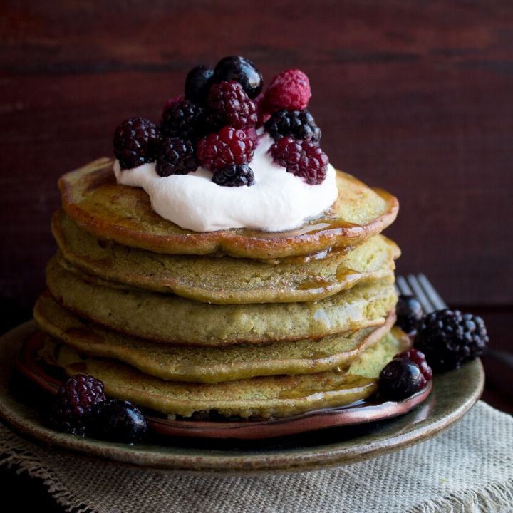 Matcha Pancakes gluten free and dairy free topped with coconut cream and berries 6 stacked high.