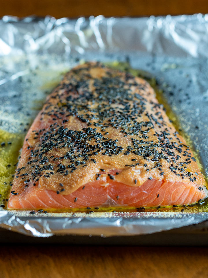 Salmon on a line sheet pan just slatethered in miso , black sesame seeds and olive oil, ready for the oven.