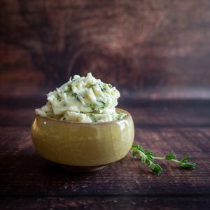 Whipped herb butter in a little yellow bowl with fresh thyme on the side.