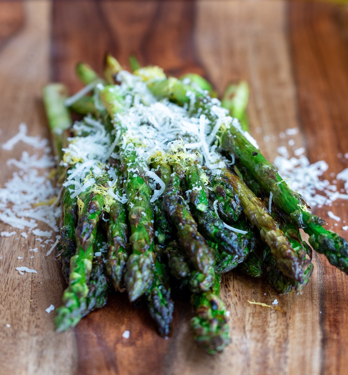 Grilled asparagus on a wooden board with lemon and parmesan.