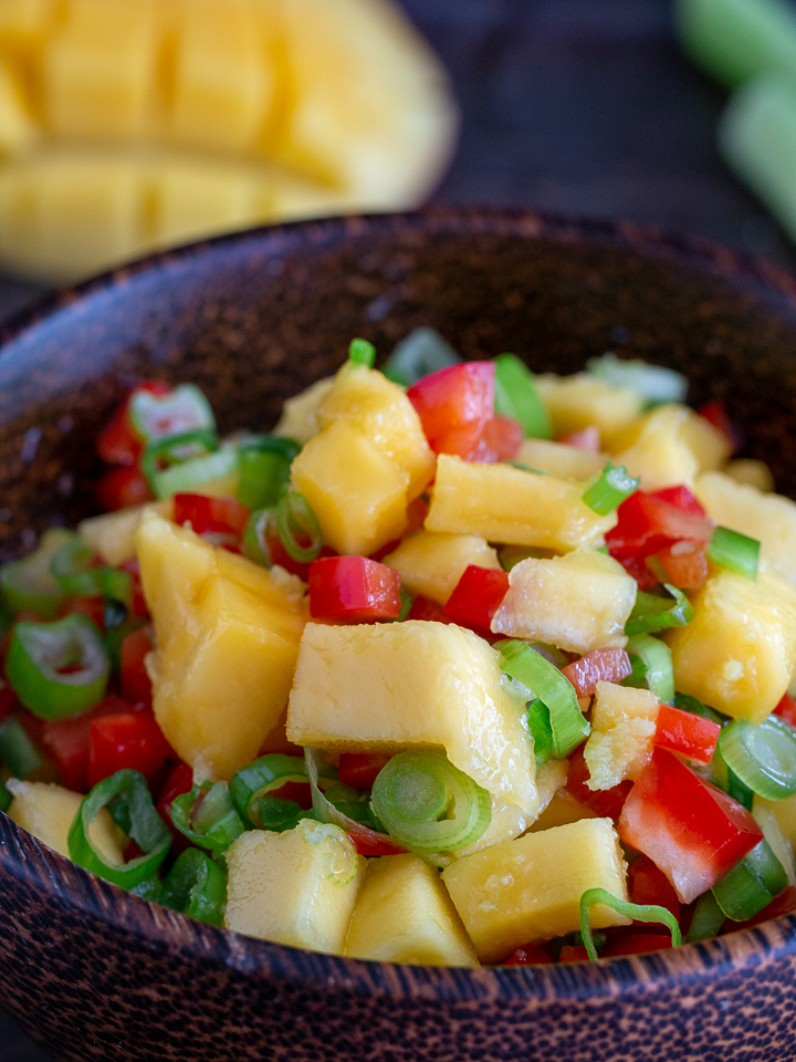 Closeup shot of tossed mango salsa in a wood bowl.