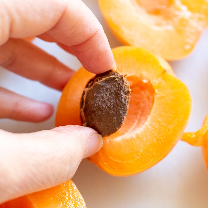 Removing pit from apricot with fingers.