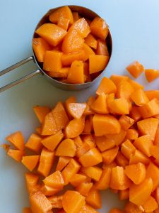 Chopped apricots on a cutting board and one cup filled.